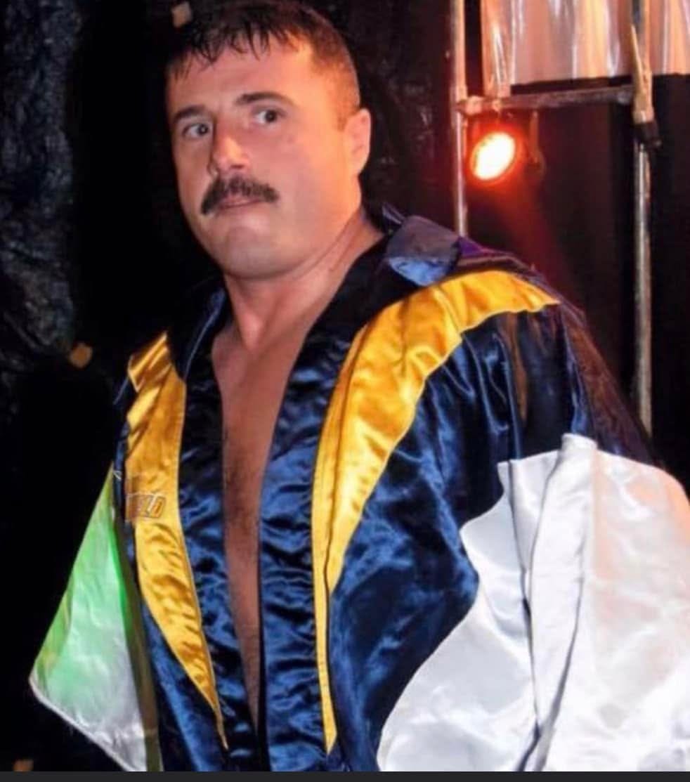 Duke Warfield in his navy and gold ring robe under arena lights